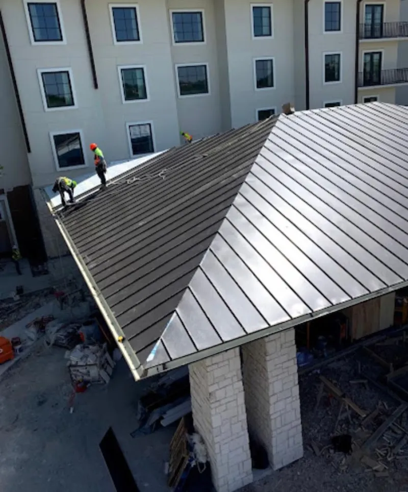 Crew installing standing seam metal roof panels on a commercial project in Somerville